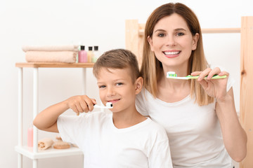 Little boy and his mother brushing teeth in bathroom