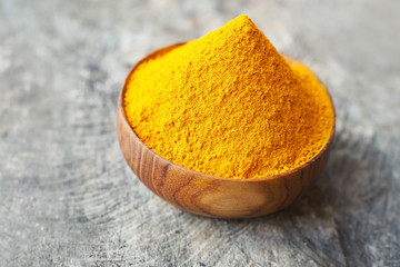 Turmeric powder in wooden bowls on wooden table. herbal