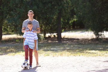 Little boy and his dad with soccer ball outdoors