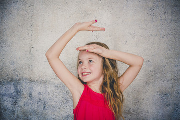 beautiful girl in red shirt in front of concrete background is posing and pointing