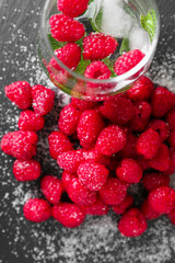 Delicious fresh ripe raspberries with sugar and cold drink on slate plate