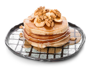 Plate with tasty pancakes, walnuts and sliced banana on white background
