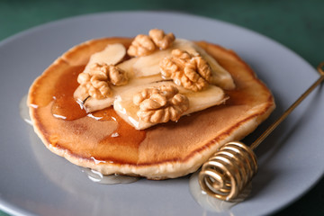 Plate with tasty pancake, sliced banana and walnuts on plate, closeup
