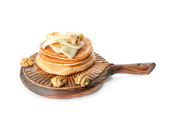 Wooden board with tasty pancakes, sliced banana and walnuts on white background