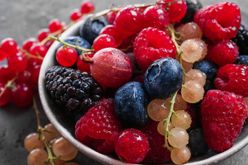 Bowl with different ripe berries on table, closeup