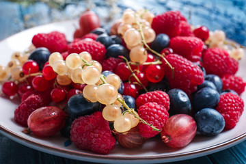 Plate with different ripe berries on table, closeup
