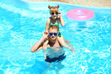 Happy father with daughter resting in swimming pool