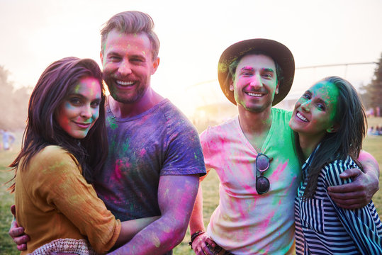 Four young adult friends covered in coloured chalk powder at Holi Festival, portrait