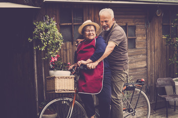 nice adult caucasian two man and woman couple laugh and have fun together on a bike in the garden...