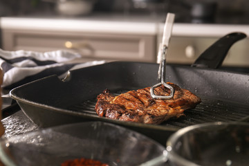 Tasty meat cooking on grill pan in kitchen