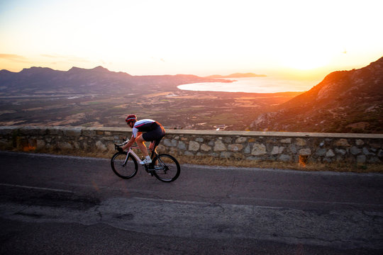 Man cycling on mountain road at sunset, Corsica, France