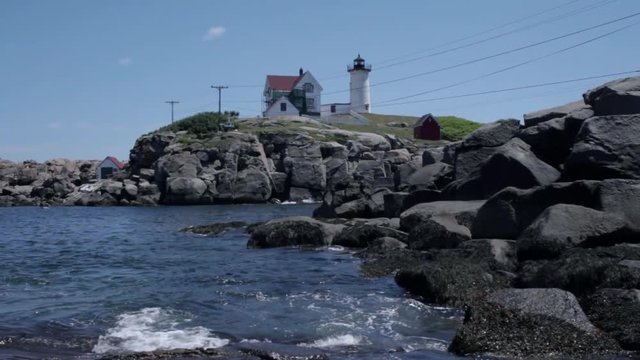 A light house in Maine with rocks in the foreground.