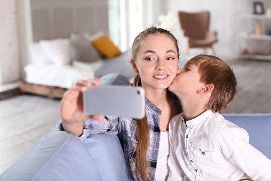 Cute little boy with his mother taking selfie at home