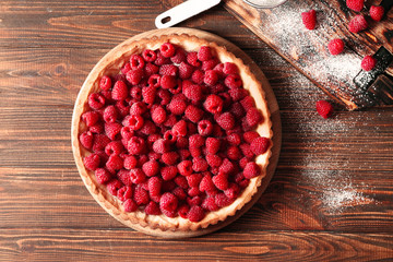 Tasty pie with fresh raspberries on wooden background