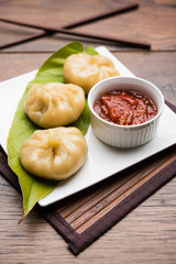 Traditional dumpling momos food from Nepal served with tomato chutney over moody background. Selective focus