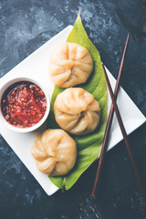 Traditional dumpling momos food from Nepal served with tomato chutney over moody background. Selective focus