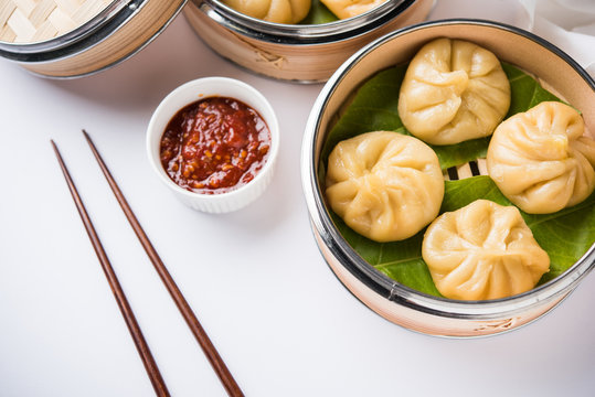 Traditional dumpling momos food from Nepal served with tomato chutney over moody background. Selective focus