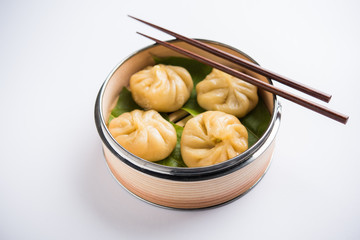 Traditional dumpling momos food from Nepal served with tomato chutney over moody background. Selective focus
