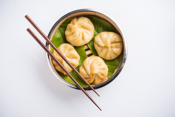 Traditional dumpling momos food from Nepal served with tomato chutney over moody background. Selective focus