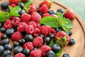 Delicious ripe berries on wooden board, closeup
