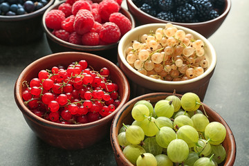 Bowls with various ripe berries on table