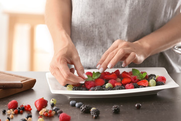 Obraz na płótnie Canvas Woman serving fresh berries on plate
