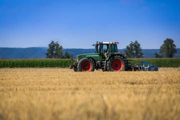 Traktor auf dem Feld bei der Arbeit, Sommerwetter   