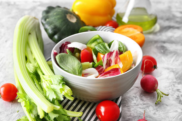 Bowl with tasty vegetable salad and ingredients on table