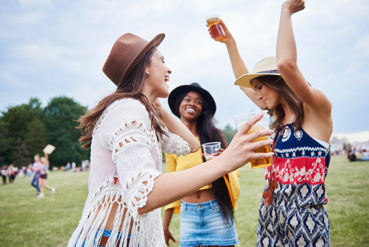 Friends drinking and dancing with arms raised in music festival