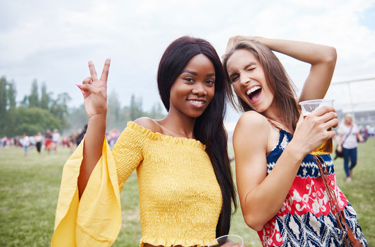 Friends drinking and dancing with arms raised in music festival