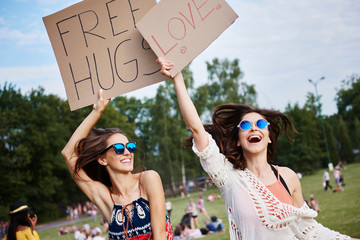 Friends holding up cardboard signs at music festival