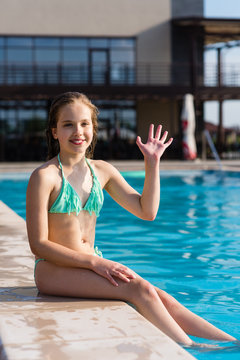 Teenage girl waving hi near pool