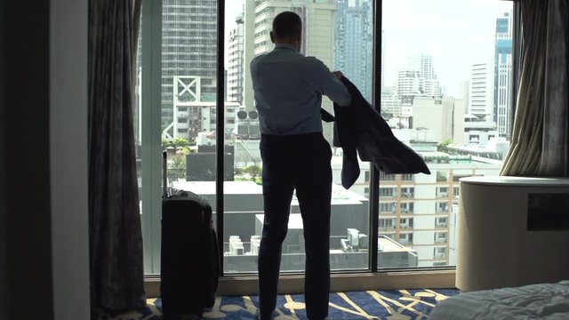 Man standing in his apartment and puts his jacket on
