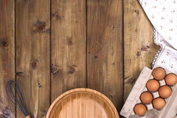 Preparation of homemade cakes on a wooden background. Ingredients and accessories for the kitchen and at home. Bowl, eggs and space for text. Top view