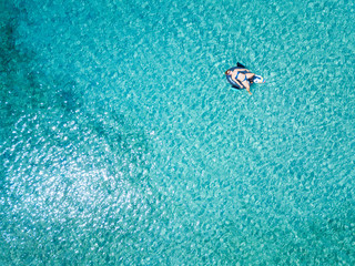 Aerial view of woman floating on the water mattress in the turquoise sea