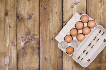 Preparation of homemade cakes on a wooden background. Ingredients and accessories for the kitchen and at home. Eggs in a box and space for text. Top view