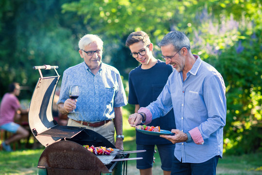  Family gathered for a bbq in the garden. men are grilling meat