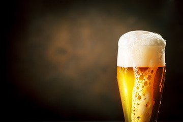 A glass of beer on a dark background.