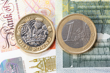 Euro coin and new pound coin isolated on cash notes background