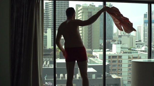 Man wearing only underwear and admiring the view from the window

