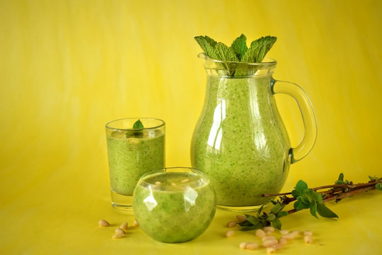 Green smoothie in glass vessels against the yellow background