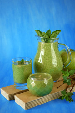 Green smoothie in glass vessels against the blue background