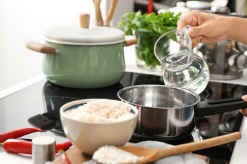 Woman pouring water into saucepan for cooking rice