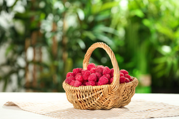 Wicker basket with fresh ripe raspberries on table outdoors