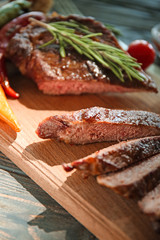 Board with tasty cut grilled meat on table