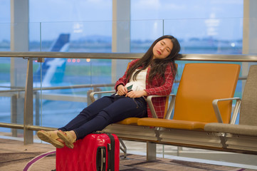 Fototapeta na wymiar young pretty tired and exhausted Asian Korean tourist woman in airport sleeping bored sitting at boarding gate hall waiting for delayed or canceled flight
