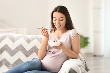 Young pregnant woman eating healthy salad at home