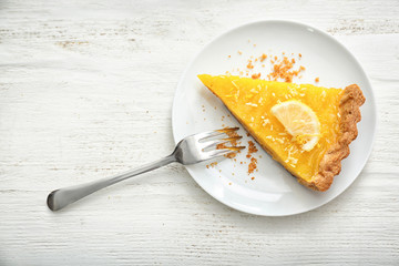 Plate with piece of tasty lemon pie on white wooden table - obrazy, fototapety, plakaty