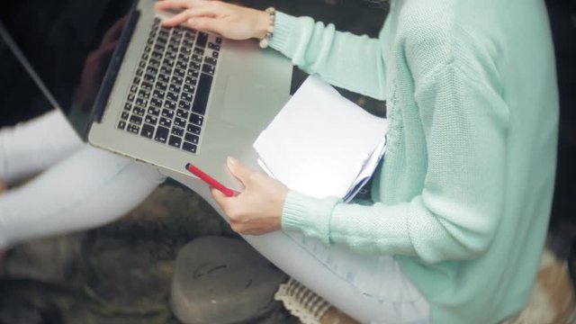 Woman with laptop and documents on the background of a stonewall wall