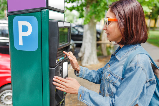 Young woman paying for parking using terminal in the street